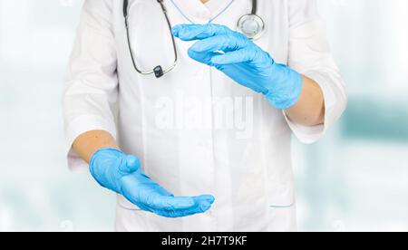 Arzt, der Platz für das Produkt oder den Text vorstellt und zeigt. Ärztin, die in medizinischen Handschuhen etwas in ihrer Hand zeigt. Stockfoto