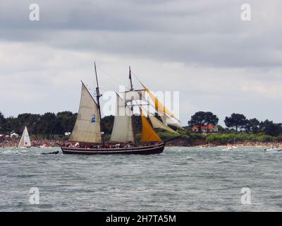 VANNES, FRANKREICH - 17. Okt 2021: Nahaufnahme des historischen Etoile de France-Segelbootes auf dem Ozean, umgeben von kleinen Booten Stockfoto