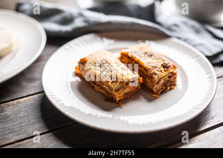 Zwei Lasagne-Stücke auf einem weißen Teller mit geriebenem Parmesankäse serviert. Stockfoto
