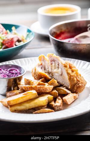 Verschiedene Mahlzeiten auf Tellern mit Cordon Bleu und gebackenen Kartoffeln vorne serviert. Stockfoto