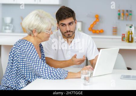 Großmutter und Enkel beobachten Familienbilder auf dem Laptop Stockfoto
