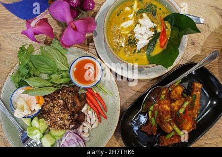 Knuspriger Schweinebauch in Erdnuss- und Kokos-Chili-Paste serviert mit frittiertem Schweinefleisch und Piper sarmentosum betel-Blätter Krabbencurry Stockfoto