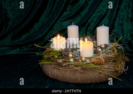 Zweiter Advent - selbstgemachter Adventskranz mit selektivem Fokus auf den Vordergrund mit zwei brennenden weißen Kerzen, eine Tradition in den vier Wochen vor Christus Stockfoto