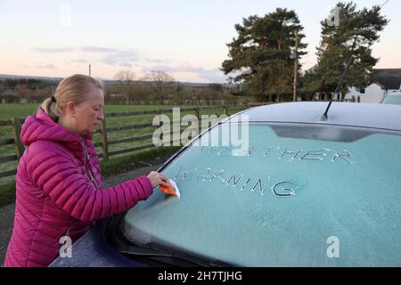 Teesdale, County Durham, Großbritannien. 25th. November 2021. Wetter in Großbritannien. Mit einer gelben Wetterwarnung vor starken Winden und Schnee für die meisten UK am Samstag räumt eine Frau Eis von ihrer Windschutzscheibe heute Morgen. Kredit: David Forster/Alamy Live Nachrichten Stockfoto