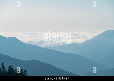 Nahaufnahme von Bergen und Wolken zwischen Bergen im Dunst Stockfoto