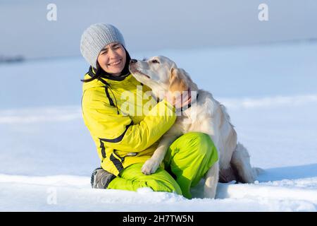 Netter Hund küsst lachende Frau Stockfoto