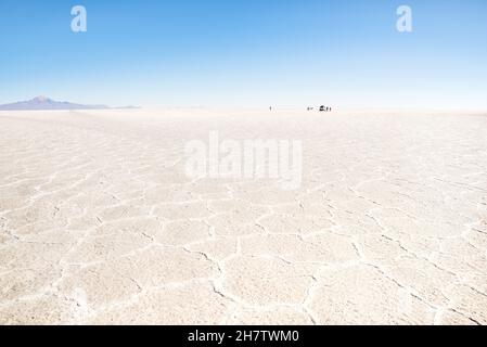 Nicht erkennbare Menschen und Geländewagen am Horizont von Salar De Uyuni - weltberühmtes Naturwunder-Reiseziel in Bolivien Stockfoto