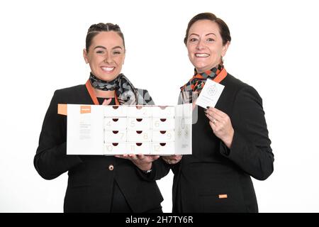 NUR FÜR REDAKTIONELLE VERWENDUNG Cabin Crew, Carla Woolley und Sam Hinton präsentieren einen neuen, limitierten „Advent(ure) Calendar“ von easyJet, der Reiseerlebnisse hinter jeder Tür zeigt, wobei der gesamte Erlös an Age UK Bedfordshire gespendet wird. Ausgabedatum: Donnerstag, 25. November 2021. Stockfoto