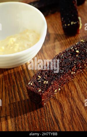 Auf dem Holztisch liegen gebratene Brotcroutons mit Sauce. Snack für Bier aus nächster Nähe. Hintergrund. Stockfoto