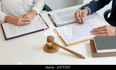 Rechtskonzept der Jurist, der ein offizielles Dokument liest, das sein Berater, der Mann in weißem langärmeligen Hemdhand an ihn hält und das Zeichen schreibt Stockfoto