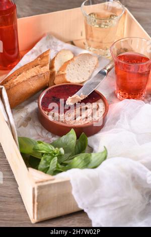 Zarte Hähnchenpastete mit pürierten Preiselbeeren, in Gelee getränkt. Serviert mit Stücken Baguette und Fruchtgetränk, in einer Holzkiste. Landestisches Essen. Stockfoto