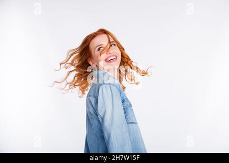 Gedreht Foto von attraktiven positiven verträumt Dame suchen leeren Raum Wind blasen Haare isoliert auf grauem Hintergrund Stockfoto