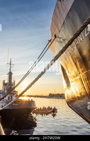 Rostock: Stadthafen, Museumsschiff-Eisbrecher 'Stephan Jantzen' (rechts), Gruppe Paddler zwischen großen Schiffen, Sonnenuntergang in Ostsee Stockfoto