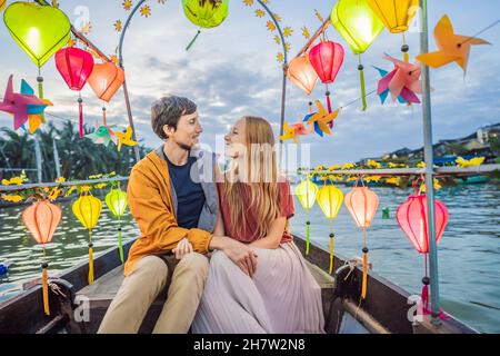 Ein glückliches Paar von Reisenden fährt auf einem Nationalboot auf dem Hintergrund der alten Stadt Hoi in Vietnam. Vietnam öffnet sich nach der Quarantäne wieder für Touristen Stockfoto