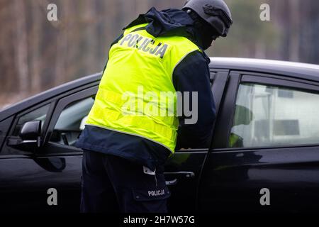 Kuznica, Woiwodschaft Podlachien, Polen. 24th. November 2021. Der Polizist wurde während der Kontrolle eines Autos gesehen, das in die Notstandszone in der Nähe der Stadt Kuznica an einer polnisch-weißrussischen Grenze einfährt. Der Ausnahmezustand, der am 2. September 2021 auf Ersuchen des Ministerrats von Präsident Andrzej Duda im Zusammenhang mit der Migrationskrise auf einem Teil des Territoriums der Republik Polen eingeführt wurde. (Bild: © Mateusz Slodkowski/ZUMA Press Wire) Stockfoto