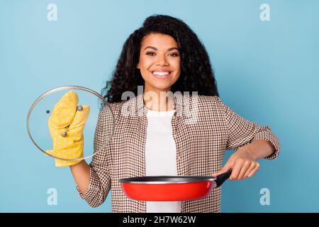 Portrait von attraktiven fröhlichen Mädchen halten Pfanne kochen gesunde Mahlzeit Rezept isoliert über bight blauen Hintergrund Stockfoto