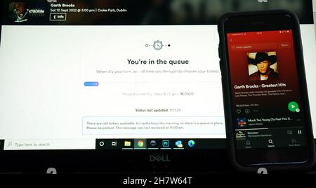 Ein Laptop, der die Ticketmaster-Buchungsseite für die kommenden Garth Brooks-Konzerte im Croke Park in Dublin zeigt, und ein Telefon, das seine größten Hits auf Spotify spielt. Garth Brooks wird nächstes Jahr fünf Konzerte in Dublin spielen, nachdem aufgrund der Nachfrage seiner irischen Fangemeinde weitere drei Termine hinzugefügt wurden. Bilddatum: Mittwoch, 25. August 2021. Stockfoto