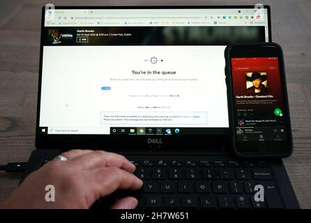 Ein Laptop, der die Ticketmaster-Buchungsseite für die kommenden Garth Brooks-Konzerte im Croke Park in Dublin zeigt, und ein Telefon, das seine größten Hits auf Spotify spielt. Garth Brooks wird nächstes Jahr fünf Konzerte in Dublin spielen, nachdem aufgrund der Nachfrage seiner irischen Fangemeinde weitere drei Termine hinzugefügt wurden. Bilddatum: Mittwoch, 25. August 2021. Stockfoto