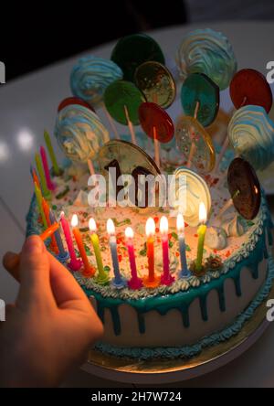 Geburtstag 18 Jahre alte Torte mit Kerzen auf dunklem Hintergrund. Leckerer Kuchen mit Zahlen 18, Lutscher und Marschmalchen auf Stöcken, brennende Kerzen. Hol Stockfoto