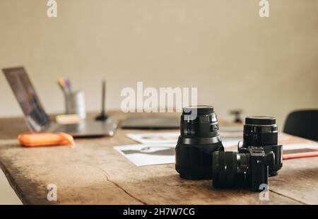 Aufnahme des Arbeitsplatzes eines Fotografen zu Hause. Standbild eines Schreibtisches mit einer DSLR-Kamera und anderen Fotogeräten. Stockfoto