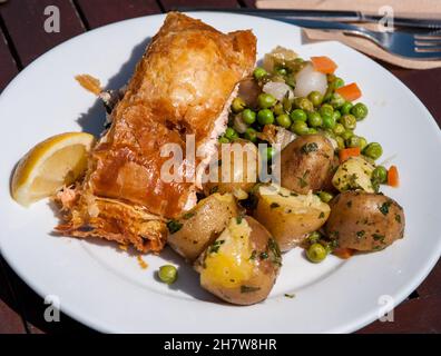 Ein köstlicher Fischkuchen mit Zitrone, gekochten Kartoffeln in Kräutern und Erbsen Stockfoto