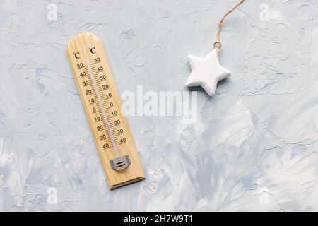 Thermometer zeigt niedrige Temperatur und Weihnachtssterne Dekoration auf weißem und blauem Hintergrund. Winter- und Urlaubswetterkonzept, Platz kopieren Stockfoto