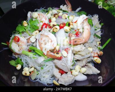 Thailändischer, würziger Nudelsalat aus Glas mit Garnelen und Schweinefleisch auf dem Teller Stockfoto