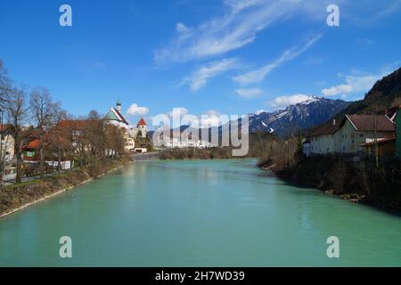 Alte deutsche Stadt Füssen am türkisfarbenen Lech mit den verschneiten Alpen im Hintergrund Mitte März (Bayern, Deutschland) Stockfoto