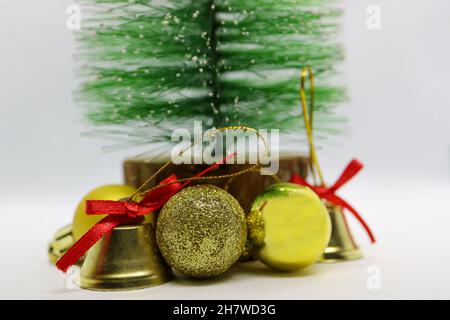 Handgefertigter Weihnachtsbaum mit goldfarbenen Glocken und Kugeln, grüner Weihnachtsbaum, Glocken mit roten Schleifen, Weihnachtsdekoration auf weißem Hintergrund Stockfoto