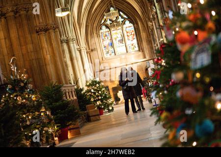 Die Besucher kommen vorbei, während die letzten Feinheiten vor der Eröffnung des berühmten Weihnachtsbaumfestivals in der Lichfield Cathedral in Staffordshire gemacht werden. Die Kathedrale wird mit 45 Weihnachtsbäumen geschmückt, von Wohltätigkeitsorganisationen, Gemeindeorganisationen, Schulen und Unternehmen geschmückt und gesponsert und wird an diesem Wochenende eröffnet. Bilddatum: Donnerstag, 25. November 2021. Stockfoto