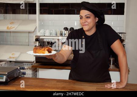 Kellnerin bietet dem Kunden einen neapolitanischen an. Kellnerin in einem Café. Lächelnde Frau. Stockfoto