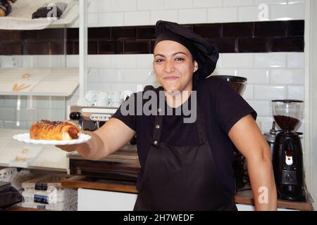 Kellnerin bietet dem Kunden einen neapolitanischen an. Kellnerin in einem Café. Lächelnde Frau. Stockfoto