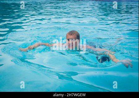 Glücklicher attraktiver Mann schwimmt im blauen Wasser eines Schwimmbades. Outdoor-Resort, Luxus-Hotel. Sommer-Spa in der Nähe des Meeres. Tropisches Paradies. Dominikanische Republik Stockfoto