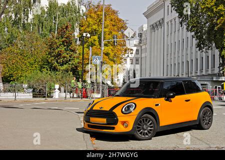 Kiew, UA - 24. August 2017: Orange Mini Cooper im Hintergrund des Staatsgebäudes Stockfoto