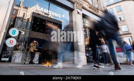 Samsung Store, Oxford Street, London. Einkäufer, die am Eingang des Elektronikladens im geschäftigen Londoner Einkaufsviertel vorbeikommen. Stockfoto