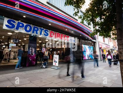 Sports Direct Store, Oxford St., London. Käufer kommen am Eingang des Flagship-Sportkettenladens im geschäftigen Londoner Einkaufsviertel vorbei. Stockfoto