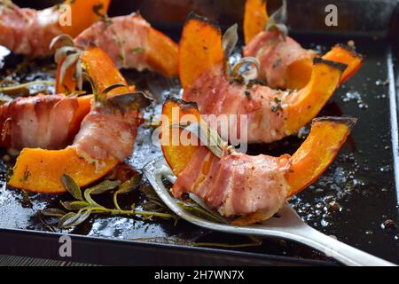 Hokkaido-Kürbislücken, eingewickelt in Speck mit Salbeiblättern und Thymian, in Olivenöl mit Pfeffer und Salz gebacken Stockfoto