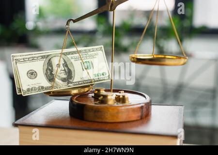 KIEW, UKRAINE - 22. SEPTEMBER 2021: Nahaufnahme der Justizskala mit Dollar auf verschwommenem Codex-Buch im Büro, Antikorruptionskonzept Stockfoto