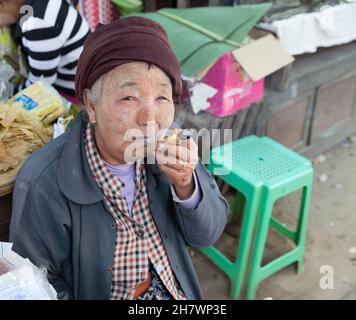 Porträt einer alten Frau, die auf dem Nyaung U-Markt Zigarren raucht Stockfoto