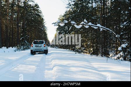 Vitebsk, Weißrussland - Februar 2021: Weißer Renault Duster auf einer verschneiten Waldstraße. Extreme Geländefahrten, 4x4. Horizontales Foto. Stockfoto