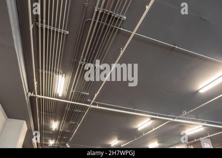 Aufgeräumte Installation von galvanisierten elektrischen Metallschläuchen (EMT) an der Decke des Parkhauses Stockfoto