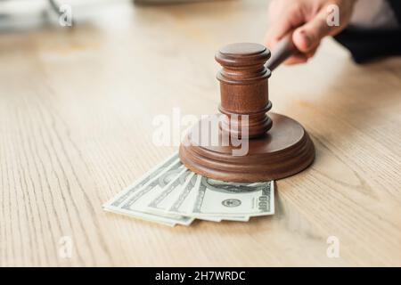 Teilansicht des Richters mit Holzgavel in der Nähe von Dollar-Banknoten auf dem Schreibtisch, Anti-Korruptions-Konzept Stockfoto