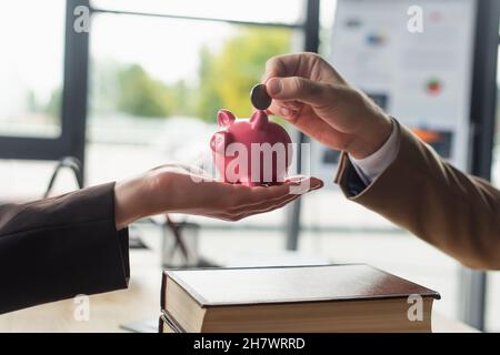 Teilansicht des Mannes, der Münzen in die Sparkasse in die Hand der Geschäftsfrau legt, Antikorruptionskonzept Stockfoto