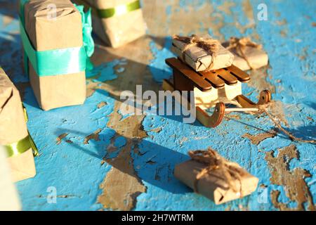 Eine eingewickelte Vintage Geschenkbox aus Holz, die auf blauem, altem Holzhintergrund liegt. Geschenk-Box in Bastelpapier mit grüner Schleife. Urlaubskonzept. Xm Stockfoto