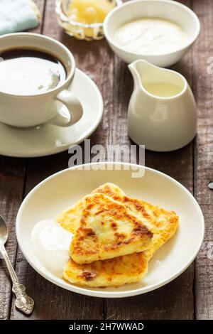 Frühstück mit Käsekuchen, Kaffee und Tee. Käsekuchen von einer ungewöhnlichen dreieckigen Form. Stockfoto