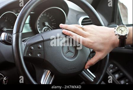 Popelnya, Ukraine - 3. November 2013: Ein Mann hält das Lenkrad von Mercedes. Uhr und einen Ring an der Hand Stockfoto