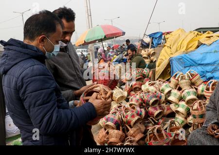 Srinagar, Indien. 24th. November 2021. Ein Kashmiri-Mann verkauft am 24. November 2021 auf einem Markt in Srinagar, Kaschmir, Indien, einen traditionellen Feuertopf Kangri. Zweige werden über einen irdenen Tontopf gewebt, um einen Kangri zu bilden. Die kangri ist mit brennender Kohle gefüllt, um die Menschen den ganzen Winter über warm zu halten. (Foto von Kamran Raashid Bhat/INA Photo Agency/Sipa USA) Quelle: SIPA USA/Alamy Live News Stockfoto