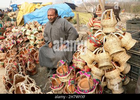 Srinagar, Indien. 24th. November 2021. Ein Kashmiri-Mann verkauft am 24. November 2021 auf einem Markt in Srinagar, Kaschmir, Indien, einen traditionellen Feuertopf Kangri. Zweige werden über einen irdenen Tontopf gewebt, um einen Kangri zu bilden. Die kangri ist mit brennender Kohle gefüllt, um die Menschen den ganzen Winter über warm zu halten. (Foto von Kamran Raashid Bhat/INA Photo Agency/Sipa USA) Quelle: SIPA USA/Alamy Live News Stockfoto