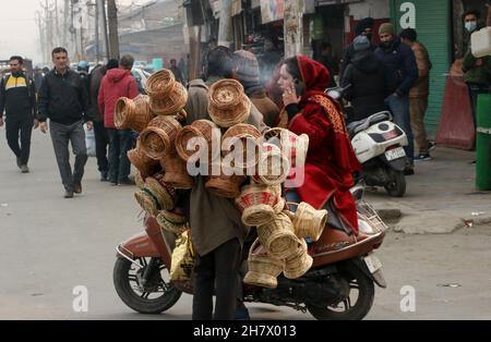 Srinagar, Indien. 24th. November 2021. Ein Kashmiri-Mann verkauft am 24. November 2021 auf einem Markt in Srinagar, Kaschmir, Indien, einen traditionellen Feuertopf Kangri. Zweige werden über einen irdenen Tontopf gewebt, um einen Kangri zu bilden. Die kangri ist mit brennender Kohle gefüllt, um die Menschen den ganzen Winter über warm zu halten. (Foto von Kamran Raashid Bhat/INA Photo Agency/Sipa USA) Quelle: SIPA USA/Alamy Live News Stockfoto