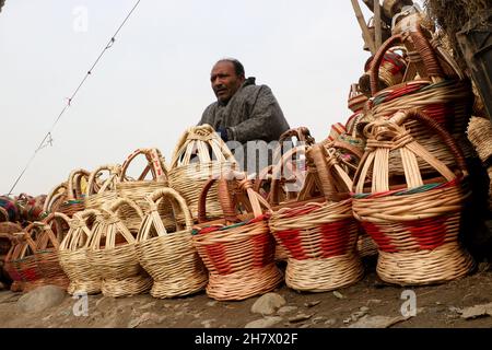 Srinagar, Indien. 24th. November 2021. Ein Kashmiri-Mann verkauft am 24. November 2021 auf einem Markt in Srinagar, Kaschmir, Indien, einen traditionellen Feuertopf Kangri. Zweige werden über einen irdenen Tontopf gewebt, um einen Kangri zu bilden. Die kangri ist mit brennender Kohle gefüllt, um die Menschen den ganzen Winter über warm zu halten. (Foto von Kamran Raashid Bhat/INA Photo Agency/Sipa USA) Quelle: SIPA USA/Alamy Live News Stockfoto